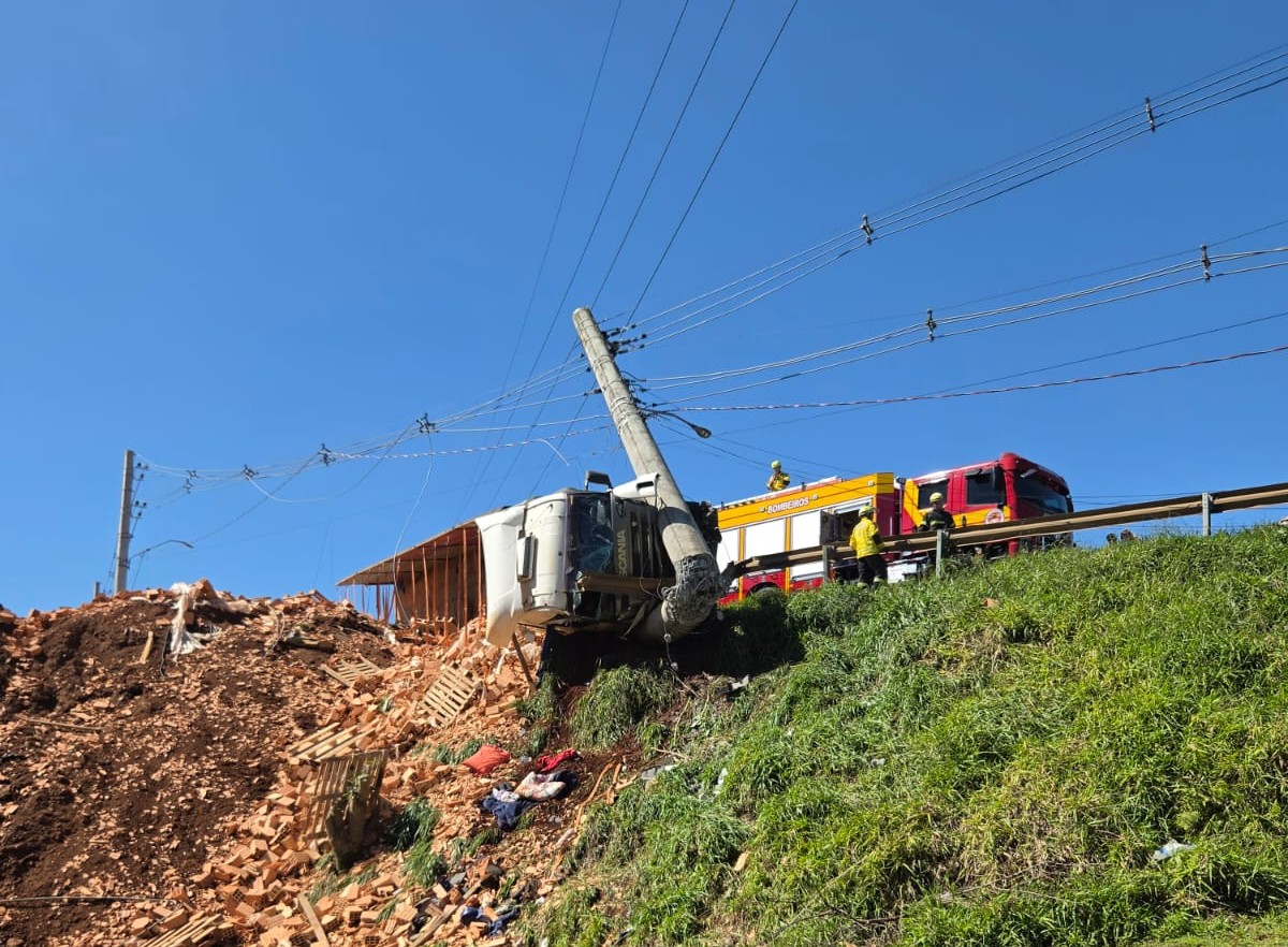 Carreta carregada de tijolos capota e bate no guard rail e em um poste de energia em Chapecó - Fotos Corpo de Bombeiros